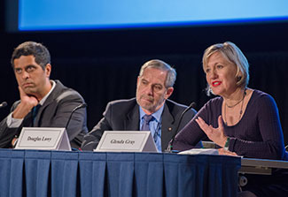 Satish Gopal, Douglas Lowy and Glenda Gray seated, speaking at panel table in auditorium