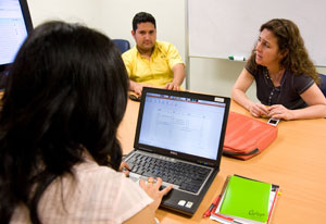 Dr Patricia Garcia seated with two researchers at conference table collaborating together while using laptop computer