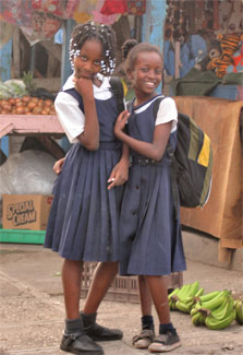 Two girls in school uniforms in open market pose for camera