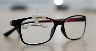 Close up for eyeglasses with small white plastic crutch for the eyelid attached.