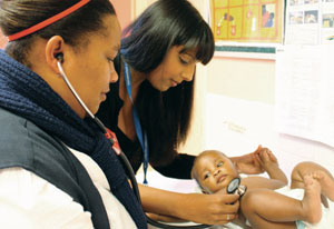 Dr. Bhakti Hansoti and healthcare worker examine infant using a stethoscope