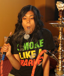 Woman smoking a water pipe hookah blows smoke rings.