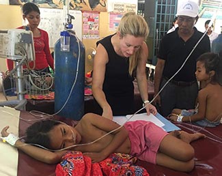 Dr. Jessica Manning works with a child patient in a clinic setting in Cambodia while others look on.