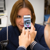 In this photo, Young Kim (foreground with his back to the camera)  uses a smart phone to take a photo of a woman’s inner eyelid. 