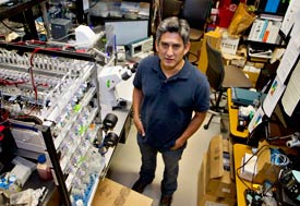 Man stands in large room filled with complex laboratory equipement