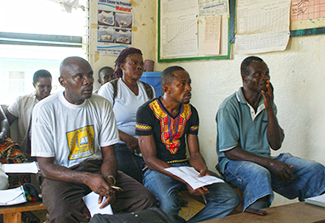 A group of men and women in Liberia sitting on wooden benches in a classroom during a training session to improve understanding of mental disorders.
