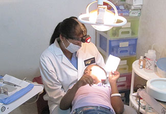 Dr Lilliam Pinzón performs a dental exam for a child in a reclined dental chair