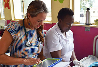 Dr. Lisa Bebell works with research nurse Honest Twinomujuni to record data in a clinic.