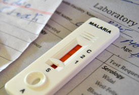 close up of white malaria test showing red indicator sitting on top of sheet of paper with title laboratory