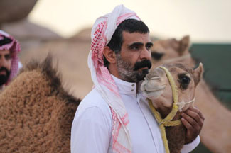 Man stands and strokes camel's neck