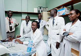 Medical student works with a patient, teacher and other students observe