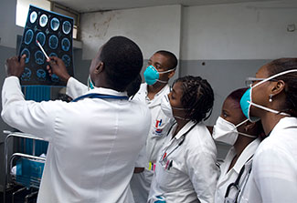 Group of medical trainees in Maputo Central Hospital, Mozambique gathers around a trainer to review x-ray held up to the light