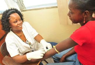 A medical worker seated across from a patient receiving treatment in a clinic in Haiti.