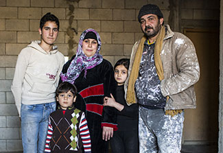 A family from Syria now living in Turkey pose for a photo: Three children, a mother and a father.