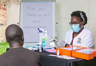 Dr. Patience A. Muwanguzi pointing to test results meets with a patient in a clinic.