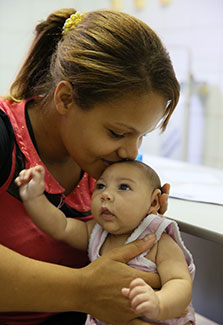 In Brazil, a mother kisses baby, who has a smaller than usual head