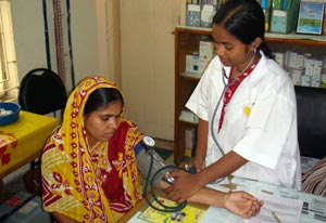 Female medical worker takes blood pressure of woman seated in a clinic