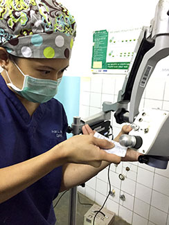 Dr. Fran Wu in scrubs and surgical mask fixes equipment used for cataract surgery