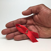 An HIV awareness ribbon in a person's hand