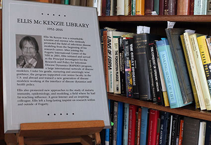 Plaque reading Ellis McKenzie Library sits on easel with shelves full of books
