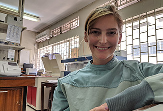 The photo shows Ashley Karczewski, DDS, smiling with lab equipment behind her 