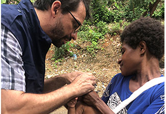 Dr. Hagan works with a mother holding her infant 