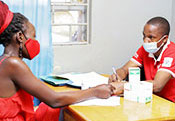 The photo shows a nurse interacting with a young woman at a family planning clinic within a government health care center in Uganda.