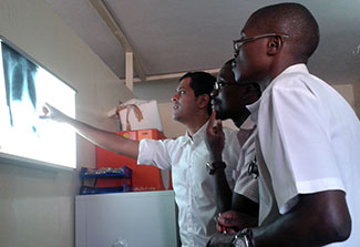 Three researchers observe chest X-ray on a light box in a dark room