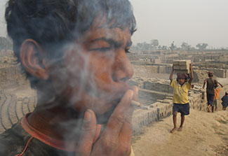 Teenage boy smokes bidi cigar outdoors in India