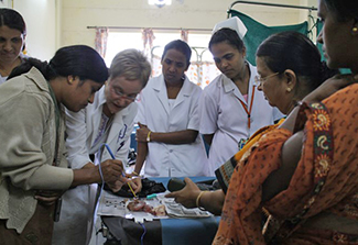 In this photo, PHRII trainees some wearing saris, learn the loop electrosurgical excision procedure for removing abnormal cervical cells from an experienced professional 
