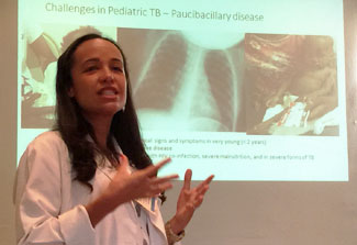 Haitian researcher Dr. Vanessa Rouzier speaks, slide on challenges in pediatric TB projected in background