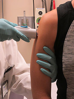 Close-up of healthcare worker wearing gloves administering Zika vaccine to upper arm of a volunteer