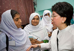 Three women in clinic wearing name badges and holding materials wait in line to sepak with Dr Margaret Chan