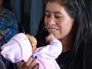 Smiling woman holds a baby close to her face.