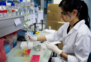 Woman researcher in white lab coat and gloves works in lab