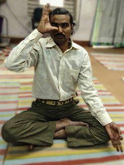 Man seated cross-legged on yoga mat with eyes closed practices alternate nostril breathing