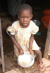 Young girl standing on the doorstep in a doorway holds a large bowl