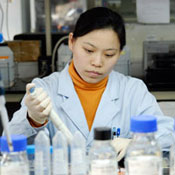 Photo courtesy of NovoNordisk R and D Center China. Woman in white lab coat surrounded by bottles and containers tops on concentrates as she put a sample in a container