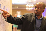 Dr. Emmanuel Balandya points to an item on a scientific poster in a conference room