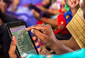 Woman uses smartphone, large group of women in the background also using smartphones