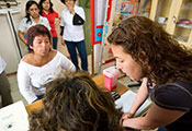 Female researcher works with female clinician while meeting with multiple female patients.