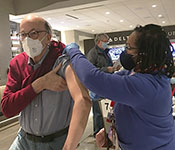 Fogarty Director Dr. Roger Glass receives a covid vaccine from a healthcare worker at a vaccine clinic.