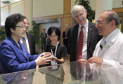 Chinese delegation gathers around architectural model in lobby of clinical center with Dr Francis Collins and Dr John Gallin