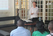 Dr Jennifer Syvertsen speaking to full classroom of students, slide projected in background