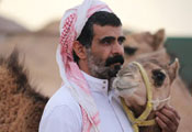 Man stands and strokes camel's neck