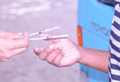 Close up of one hands of one person passing two syringe needles to another person