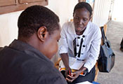 Female researcher collects data with pen and paper from female research participant who is seated across from her