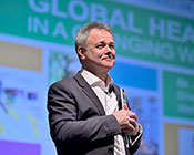 Dr. Jeremy Farrar smiles while standing on stage after presenting the Barmes Global Health Lecture.