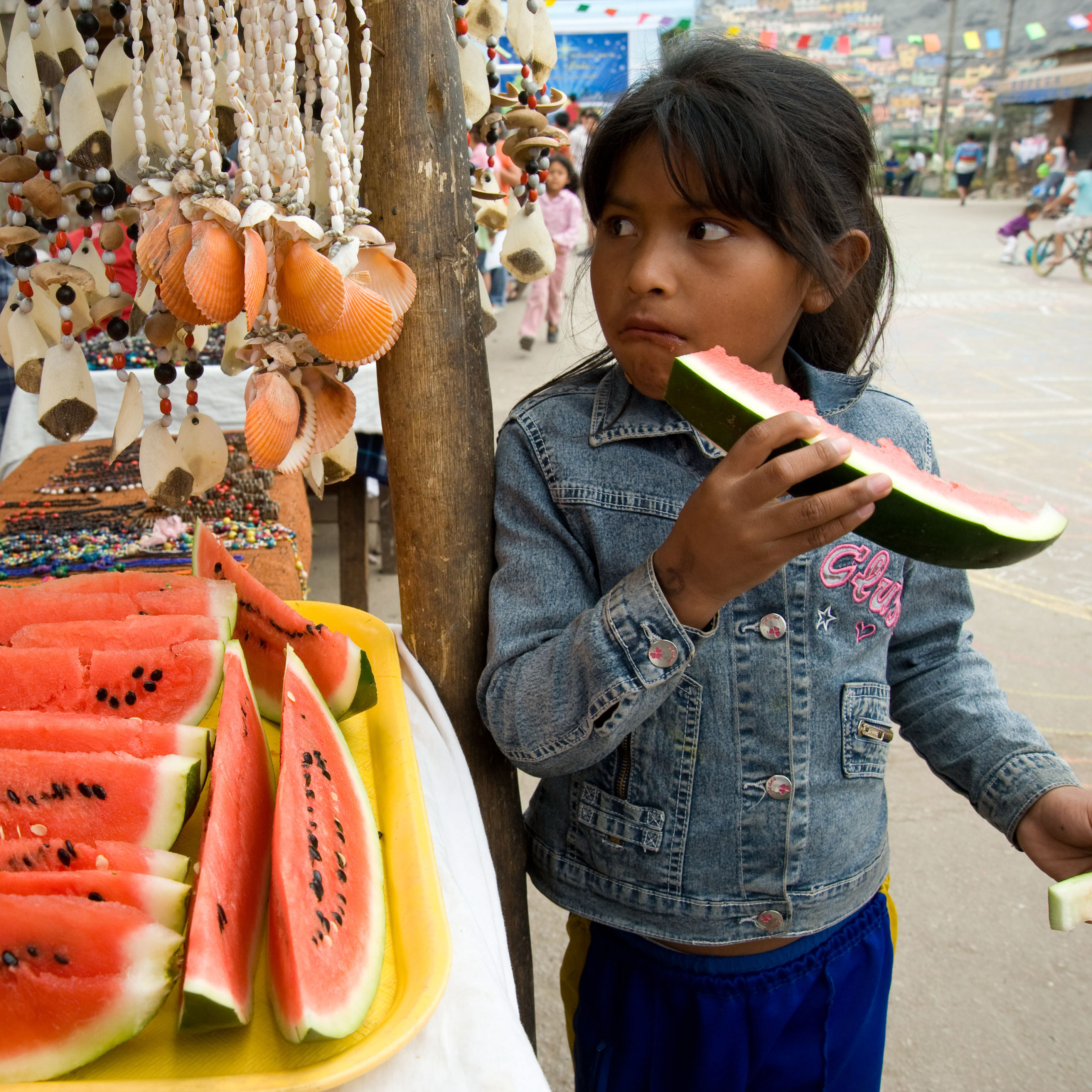 Prawn farming Latin American girl eats watermelon outside a street vendor stall
