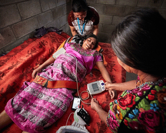A pregnant woman is screened by two health workers with a mobile health (mHealth) app in rural Guatemala